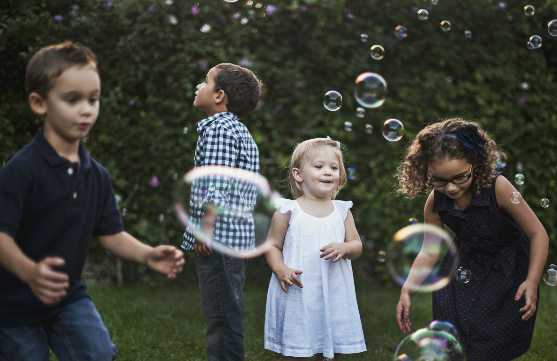 Children playing with floating bubbles in a green park
